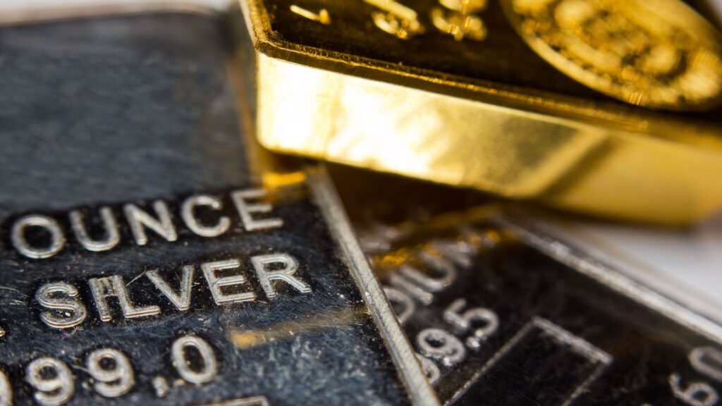 A collection of gold and silver bars neatly arranged on a wooden table.