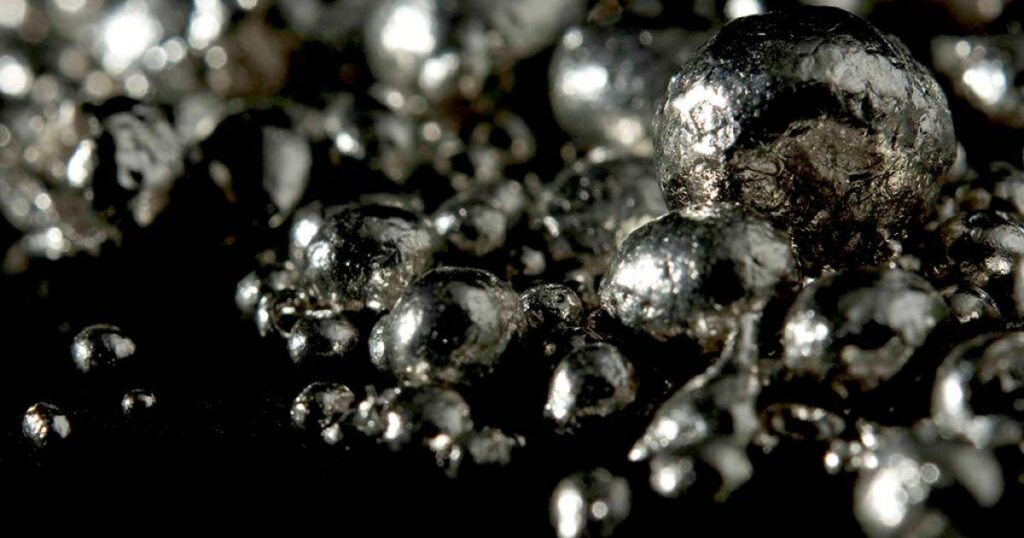 A close-up view of a pile of shiny silver balls stacked together, reflecting light in various directions.
